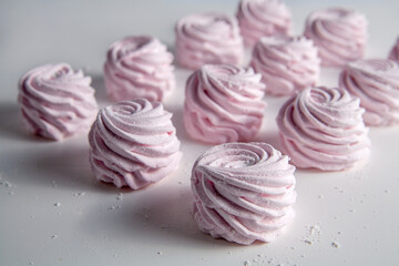 There is a pink marshmallow on the table. On a white background. Selective focus.