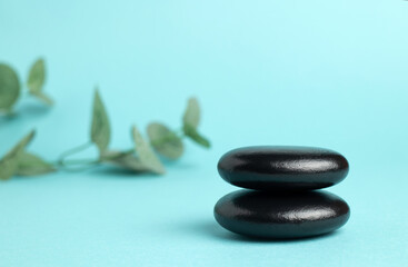 A stack of black zen balance stones on a blue background. The concept of a SPA center. A stage for promotion, sale, presentation or cosmetics. Copy space