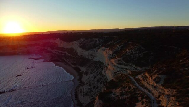 Drone flight over the Mediterranean coast over the forest and rocks in the rays of sunset in Cyprus. Zapallo bay.