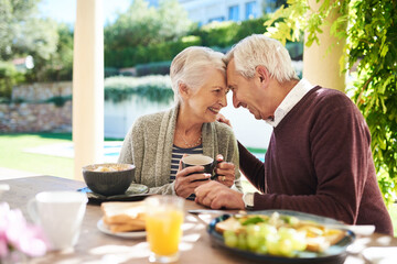 Romance keeps our love burning strong. Shot of an affectionate senior couple enjoying a meal together outdoors.