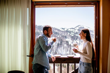 Young couple with cups of hot tea at winter window