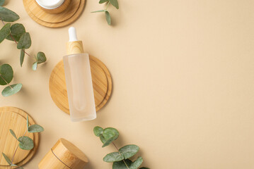 Top view photo of transparent bottle with liquid cosmetics bamboo stands and eucalyptus on isolated beige background with copyspace
