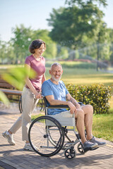 Obraz premium A dark-haired woman carrying her husband in a wheel chair