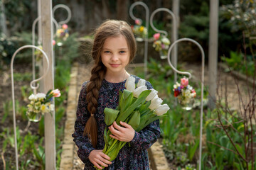 Cute smiling little girl  with tulips bouquet in hands outdoor