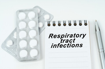 On a white surface are pills in a package, a pen and a notepad with the inscription - Respiratory tract infections