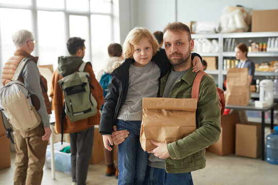 Waist up portrait of father and son holding food donations at volunteer center for refugees and people in need, copy space