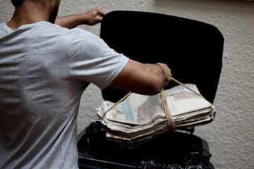 Organisation is key. Shot of a young man putting newspaper in the bin to be recycled.