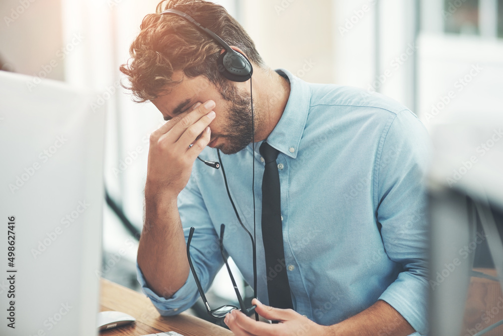 Poster Dealing with difficult clients. Shot of a young man experiencing stress while working in a call center.