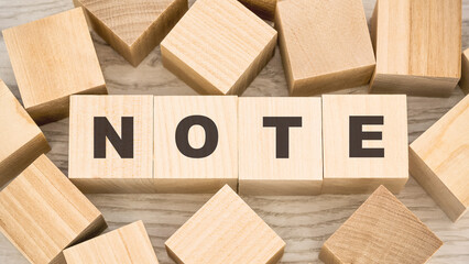 word note with black letters on toy wooden cubes and numerous blank details on light table view from above