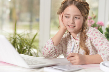 cute little girl using laptop at home