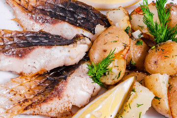 Carp steak with baked potatoes on a white plate