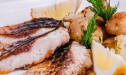 Carp steak with baked potatoes on a white plate