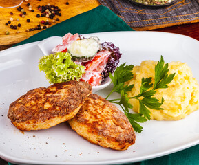 Chicken cutlets, mashed potatoes and vegetable salad on a white plate