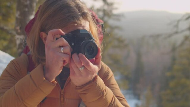 Professional photographer taking pictures of winter nature with camera while hiking in mountains