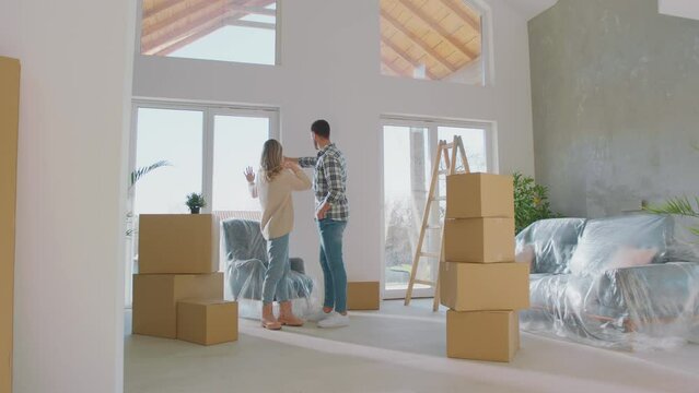 Happy young couple is moving a new house. They are discussing about home decration.