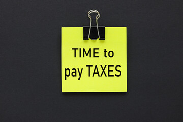 Time to pay taxes. text on yellow sticker. on a black background