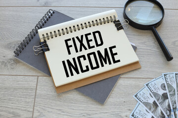 Fixed income open notepad with text on gray notepad near magnifier and money