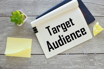 Target audience text on an open notebook on an envelope with money. next to a potted plant