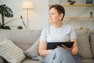 people, technology and internet concept - happy middle aged woman with tablet pc computer at home.