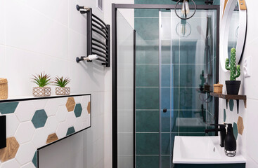 Modern interior of bathroom with cabin of shower and green tiles on the wall. Stylish pattern tile and bathroom sink in washroom at home.
