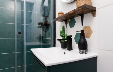 Modern interior of bathroom with ceramic washbasin with tap, shower with green tiles, ane pattern...