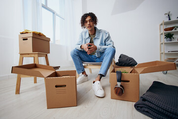 handsome guy sitting on a chair with boxes moving interior