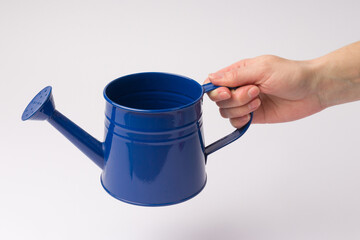 human hand holding a blue watering can for plants