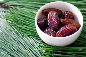 Juicy date fruit selective focus on a green pine leaf. The most consumed fruit in Ramadan