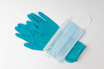 a pair of blue medical gloves and a disposable mask on a white background