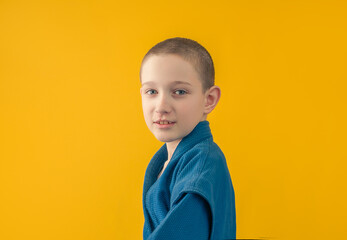 boy in blue sportswear stands sideways, yellow background