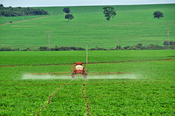 Trator fazendo pulverização em campo com ceu azul