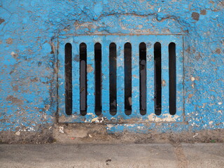 Rejilla de alcantarillado en suelo pintado de azul