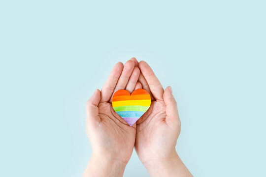 International Day Against Homophobia, Transphobia and Biphobia. May 17. Stop Homophobia. Heart with rainbow LGBT flag in the hands on a blue background.