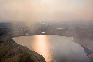Aerial view of a huge wildfire on high level moorland next to a reservoir (Llangynidr Moors, Wales)