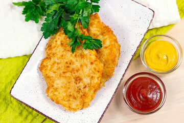 Top view of roasted meat in breading with cheese  and different sauces for dinner.