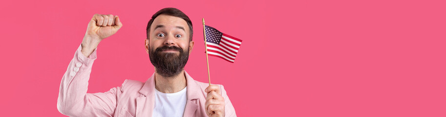 Portrait of a satisfied young man with a beard with an American flag on a red studio background. Great US patriot and defender of freedom.