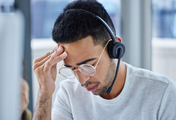 Work is piling up faster than I can handle. Shot of a young businessman suffering s headache at his...