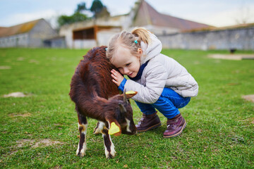 Adorable little girl playing with goats at farm