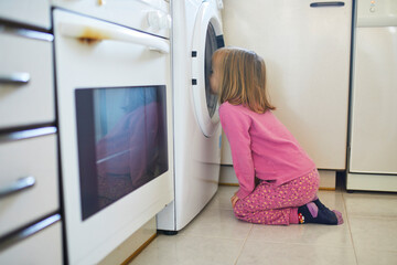 Fototapeta na wymiar Preschooler girl watching into the washing machine