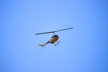 Helicopter Robinson R44 flies in the blue sky