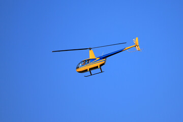 Fototapeta na wymiar Helicopter Robinson R44 flies in the blue sky