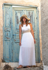 Naklejka premium Young beautiful pretty white woman in Oil old town in Santorini greek island in Greece near blue door and white buildings in summer. High quality photo