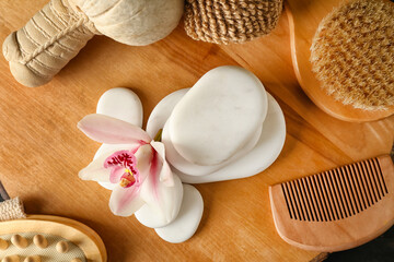 Spa stones with herbal bag and bathing supplies on wooden board