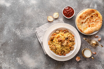 Plate of traditional pilaf with flatbread and Aladdin lamp on grunge background