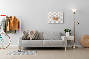 Interior of stylish living room with sofa, glowing lamp and stylish jackets