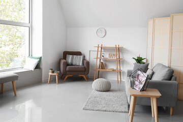 Interior of light living room with soft armchair, sofa and shelving unit