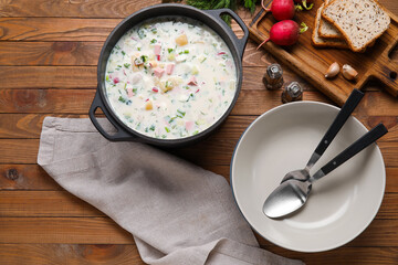 Cooking pot of tasty okroshka and ingredients on wooden background