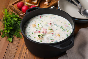 Cooking pot of tasty okroshka on wooden background