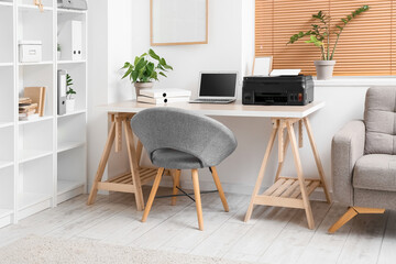 Workplace with modern laptop and printer in office interior
