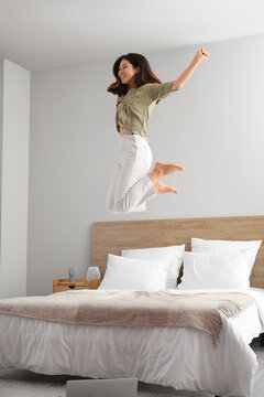 Young Asian Barefoot Woman Jumping On Bed At Home